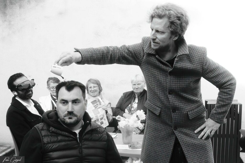 Man sitting during a scene directed by another man