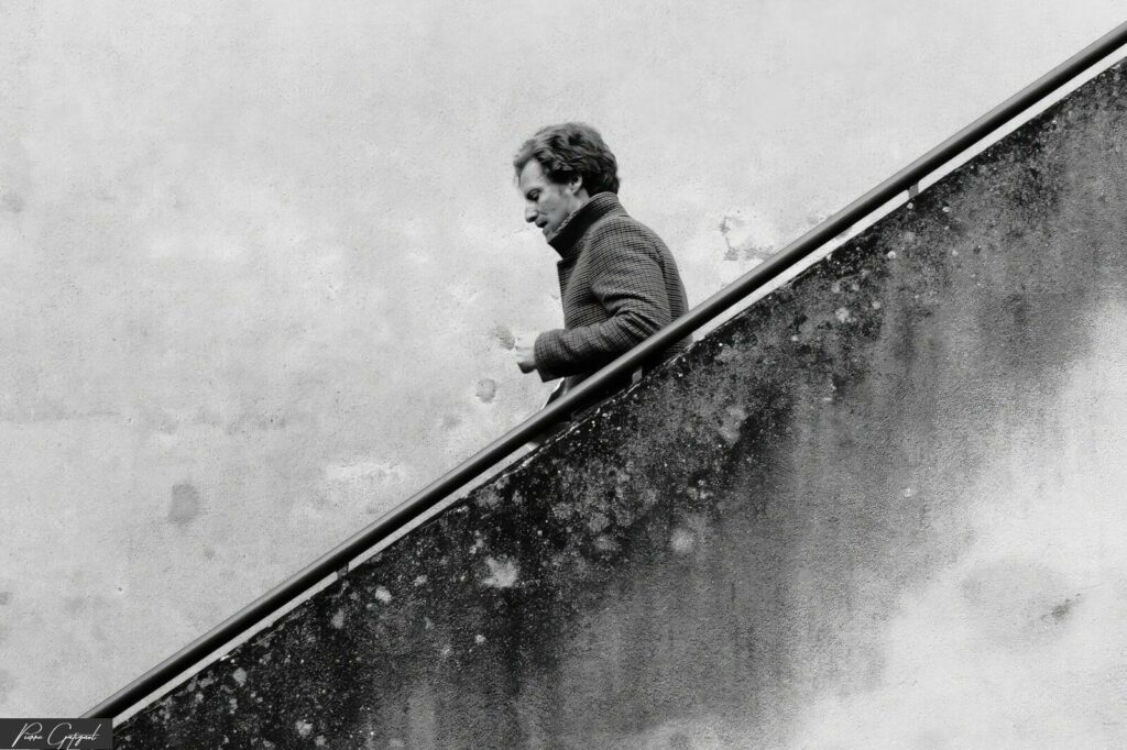 Man walking down an outdoor staircase in black and white