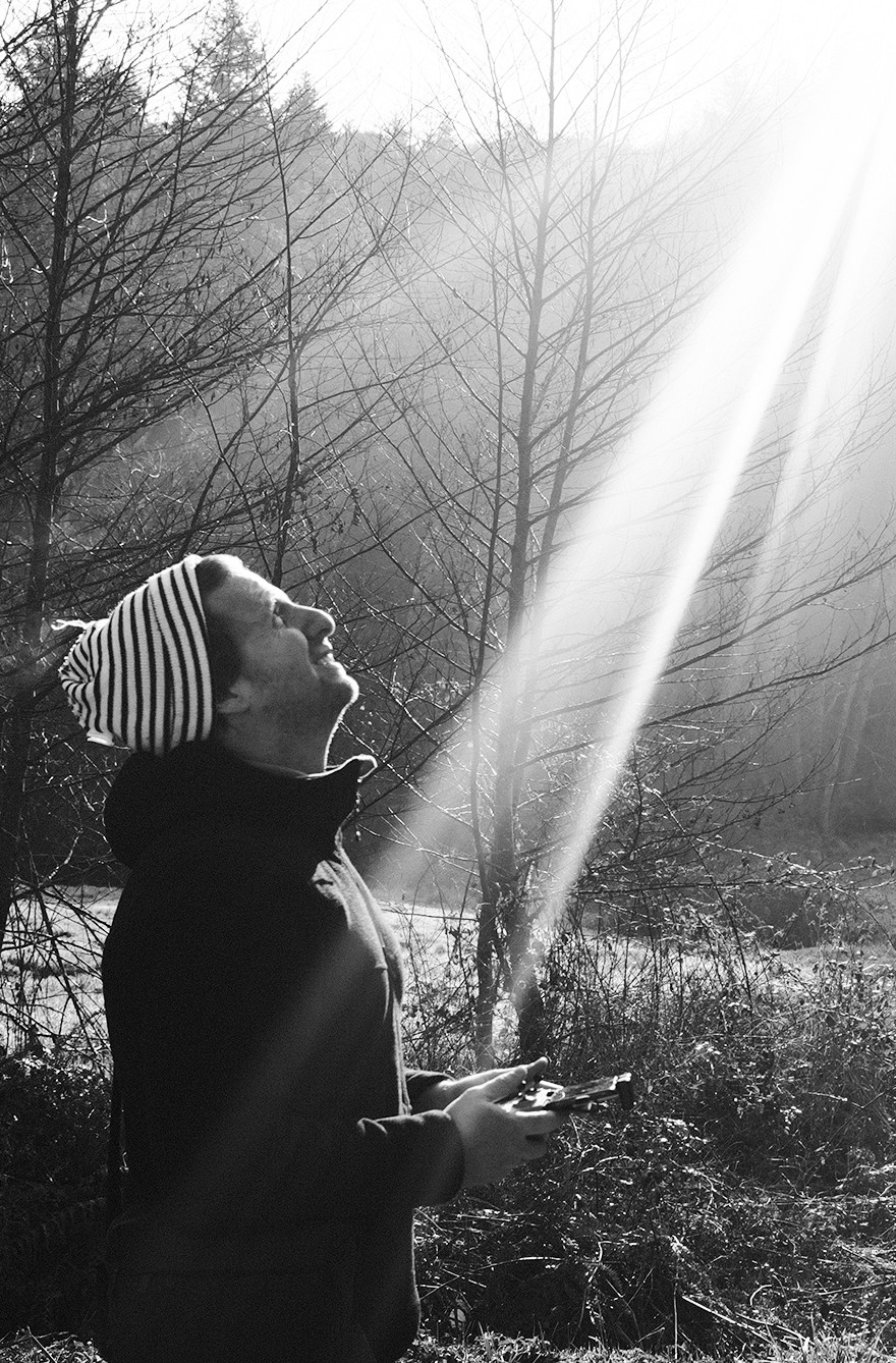 Outdoor portrait of Christopher Tourneur Person in a striped beanie looking at a ray of sunshine