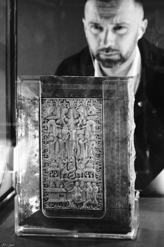 Antique book displayed under a glass case, man in the background