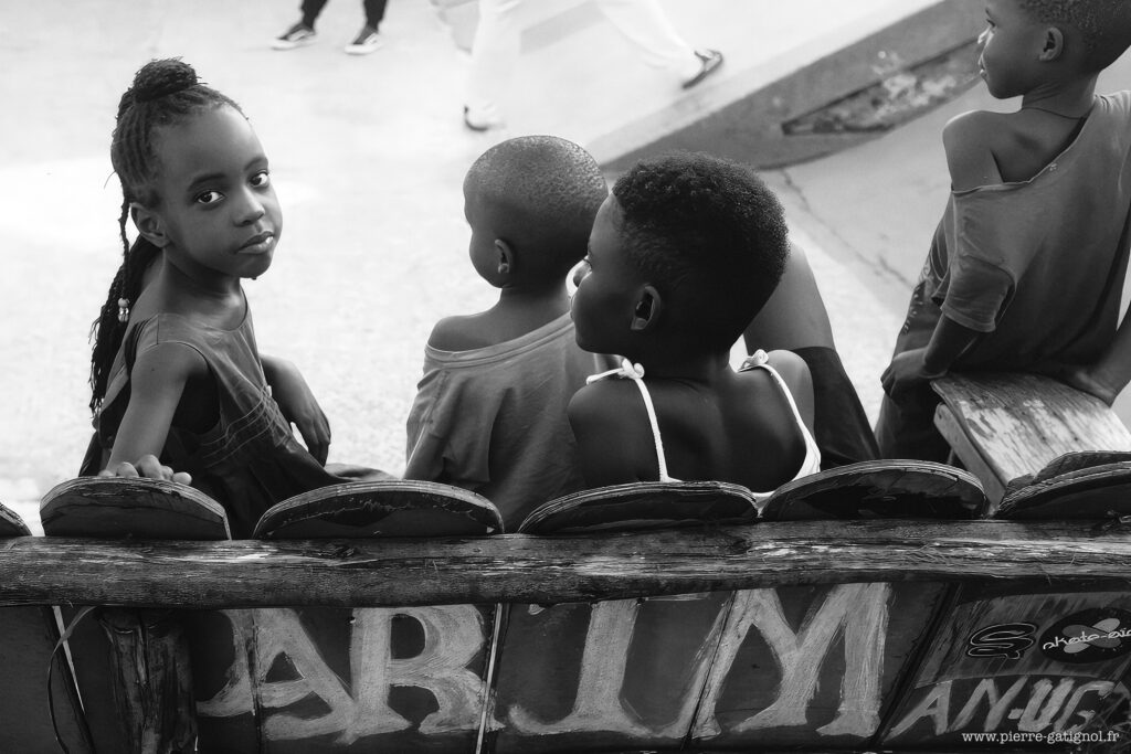 Children sitting on a bench, one looking at the camera